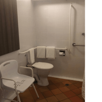 bathroom with shower chair, handrails & shower curtain