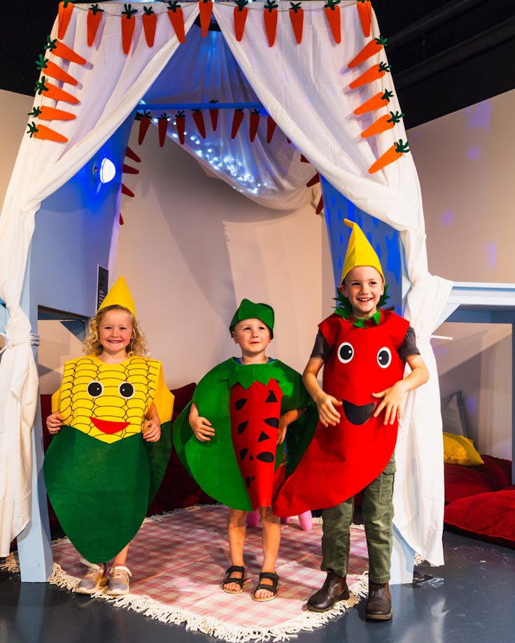 Three children dressed as fruits and vegetables at Hop In