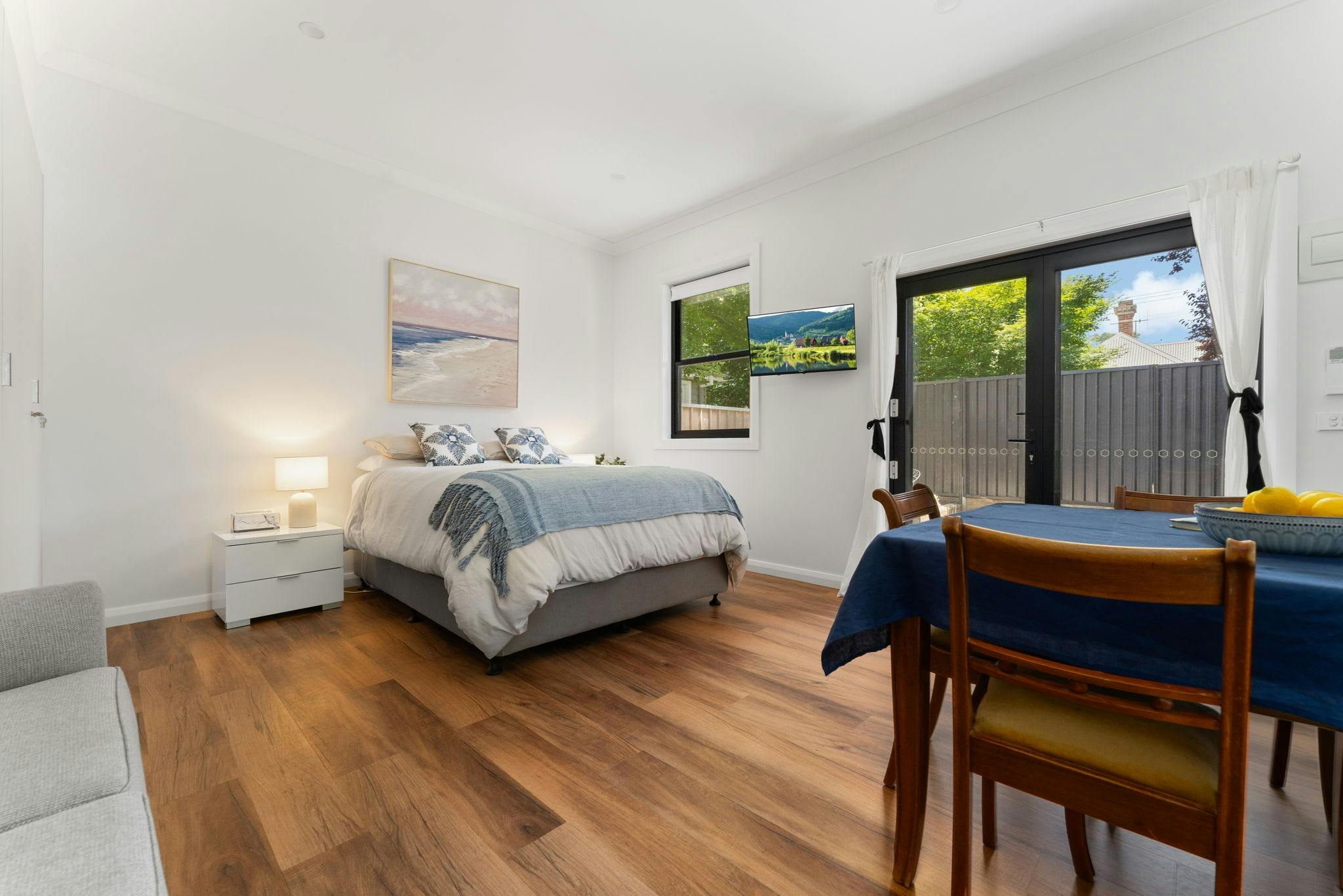 Queen Bed with small dining table, side tables and tv mounted on wall