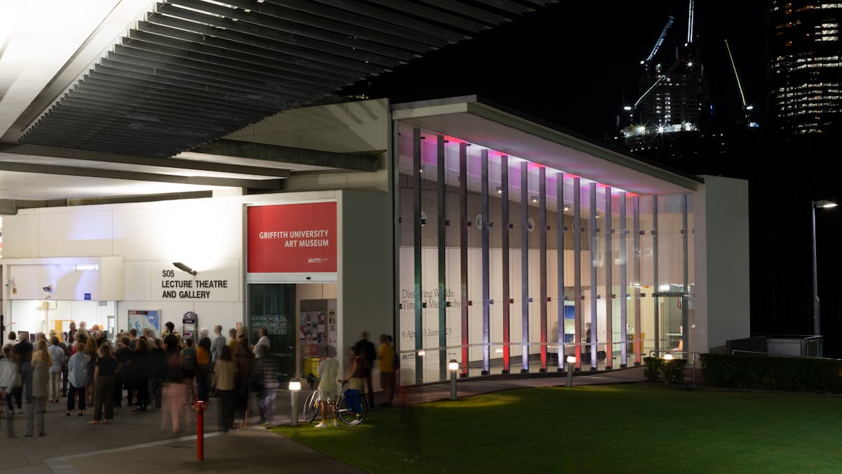 Exterior view of Griffith University Art Museum at nigh, with a large crowd