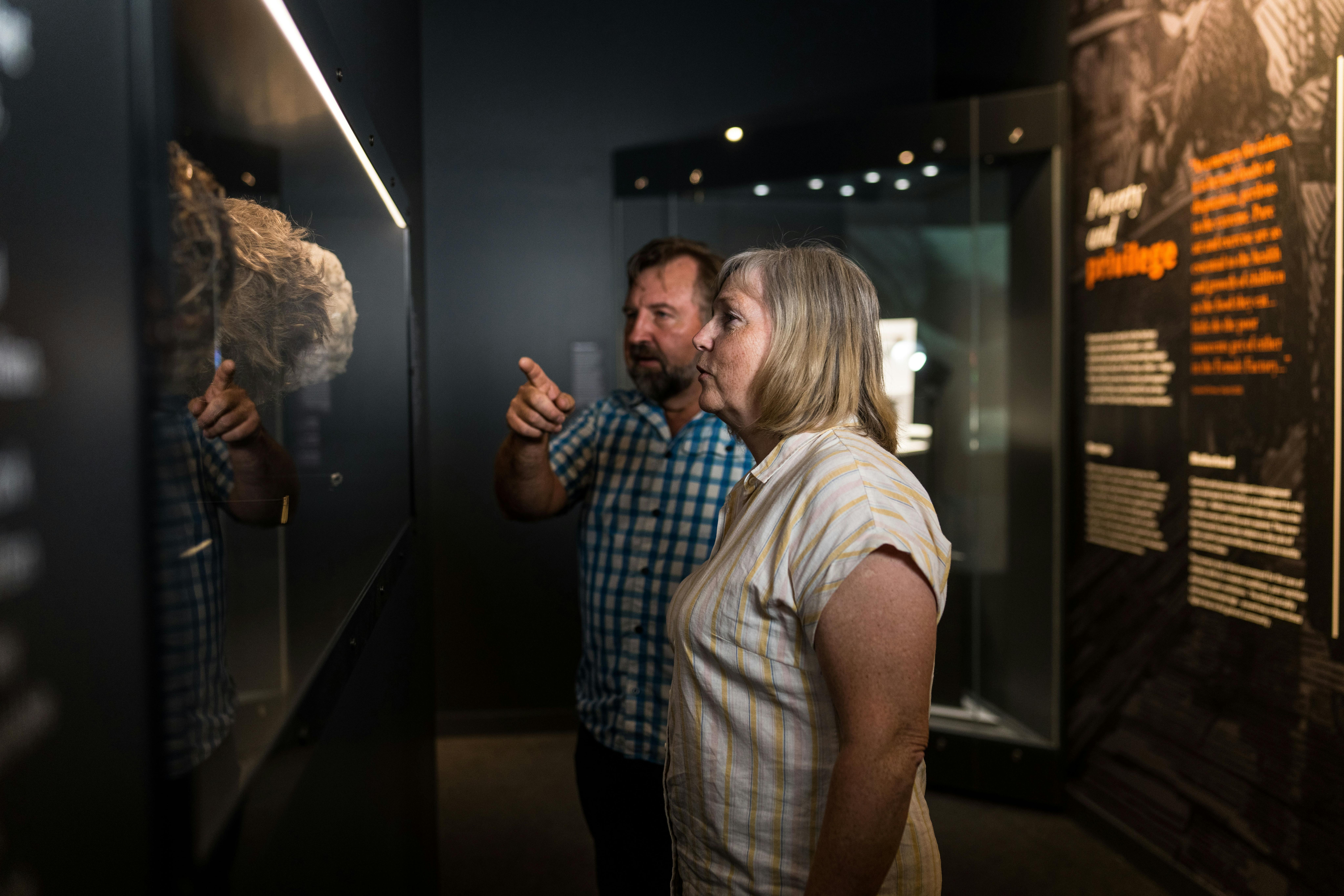 A couple looking at the exhibition in the dark lighted gallery