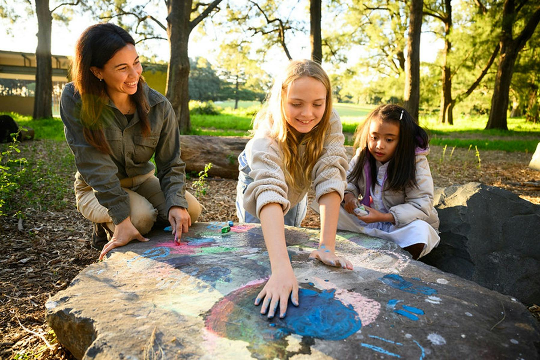Children drawing with chalk on wooden stump outdoors