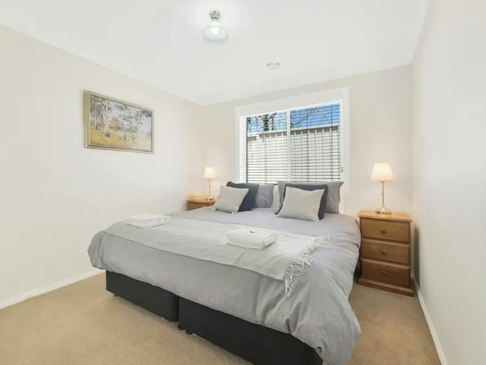 King bed with wooden side tables, artwork and a window