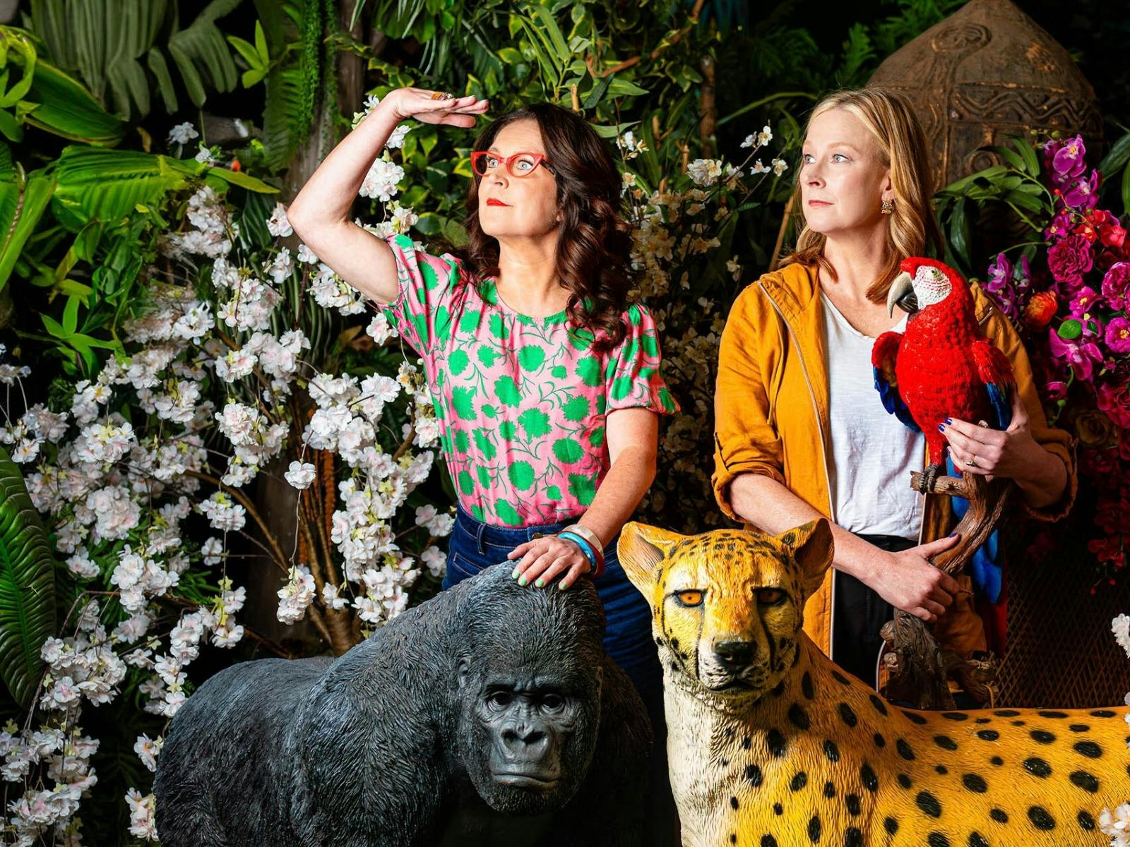 Leigh Sales and Annabel Crabb with a gorilla, cheetah, and macaw in a jungle setting
