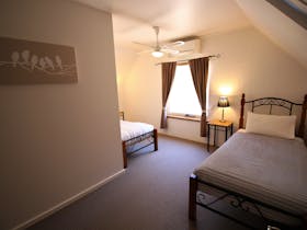 One twin bedroom with two single beds, a ceiling fan and air conditioning