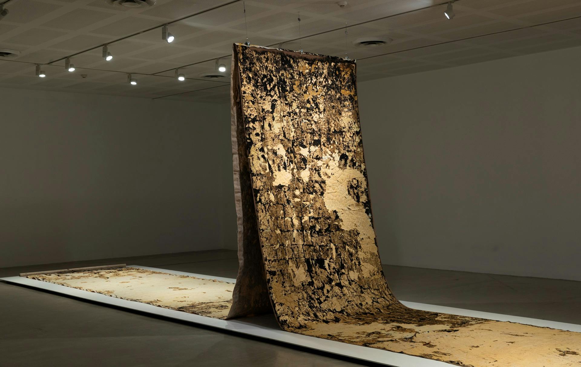 Installation image of Kirtika Kain's installation of  gold, bitumen, and turmeric print works