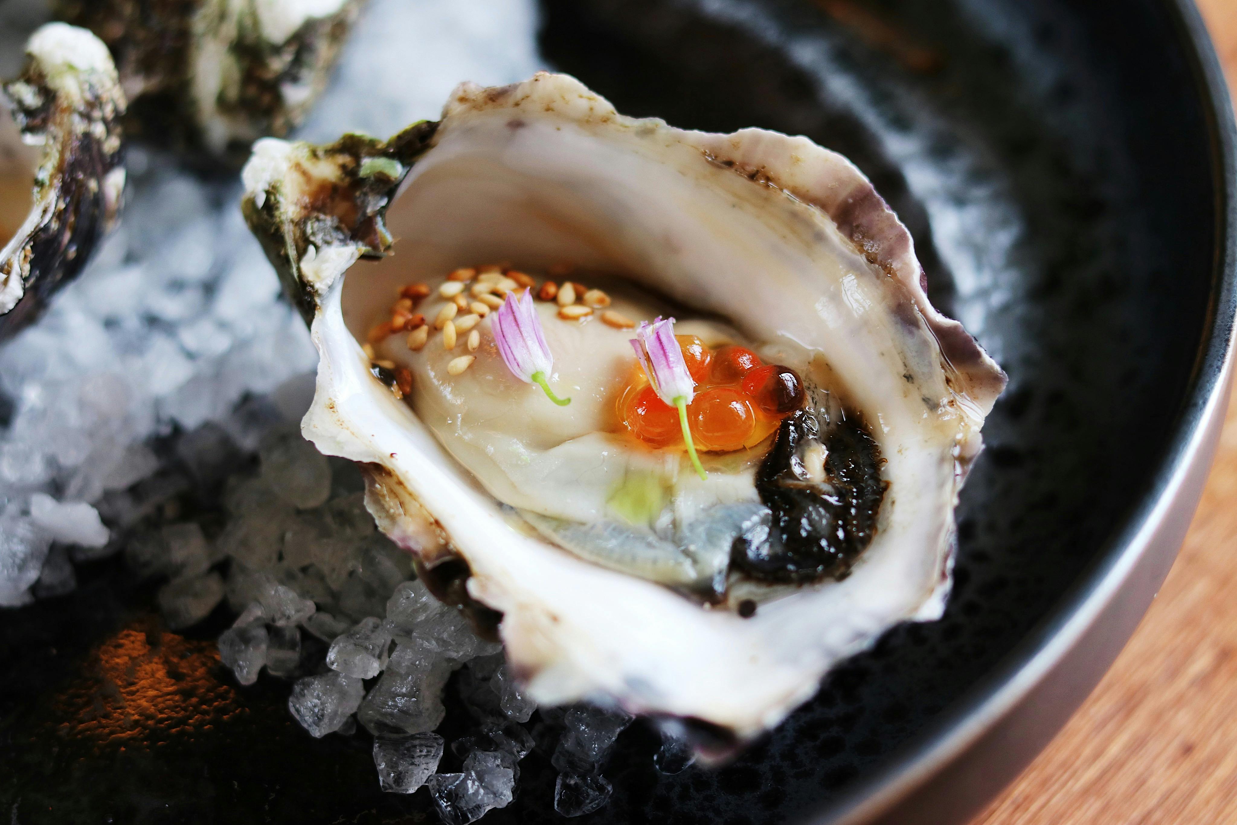 Close-up photo of an oyster garnished with roe and edible flowers