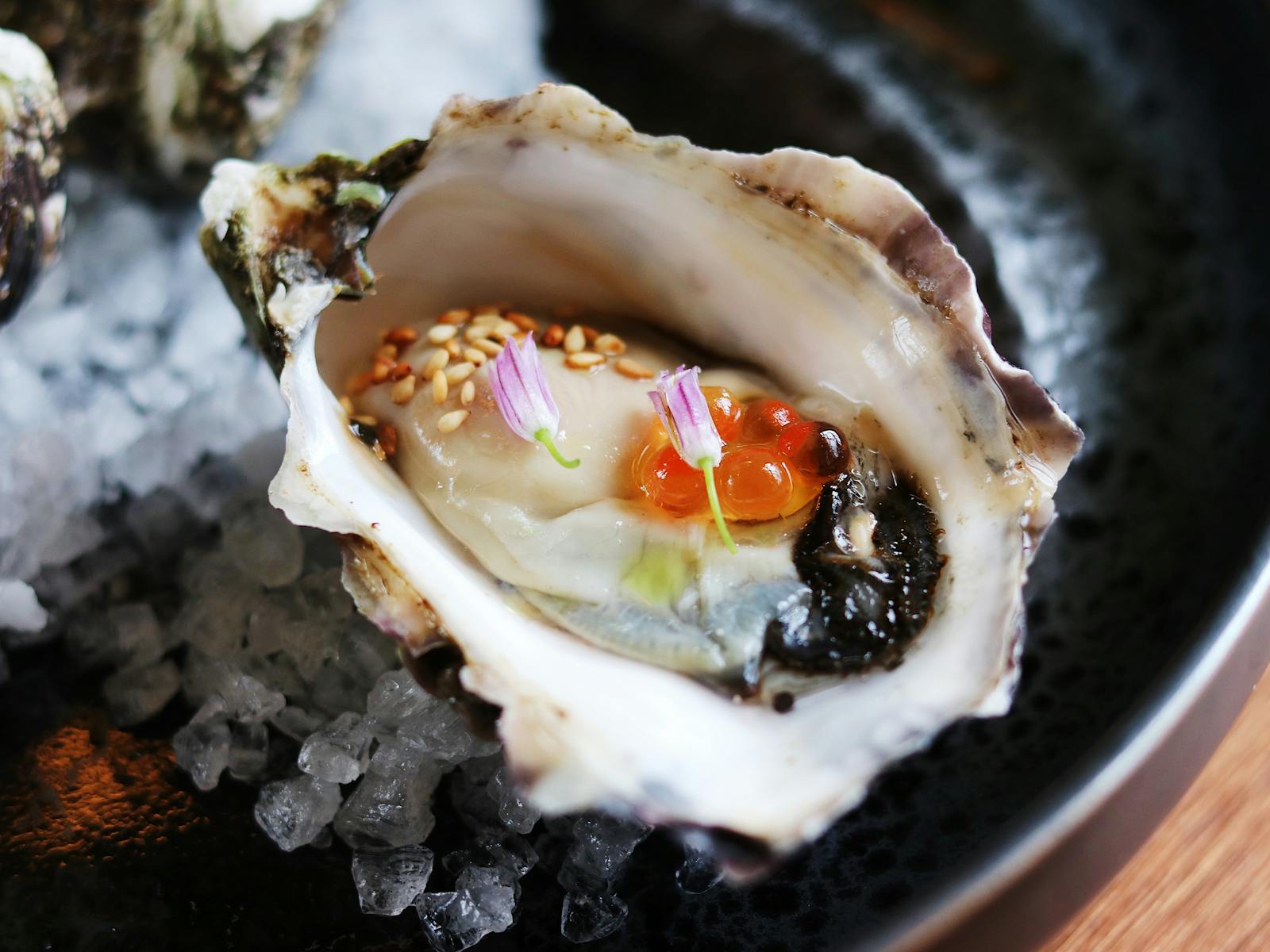 Close-up photo of an oyster garnished with roe and edible flowers