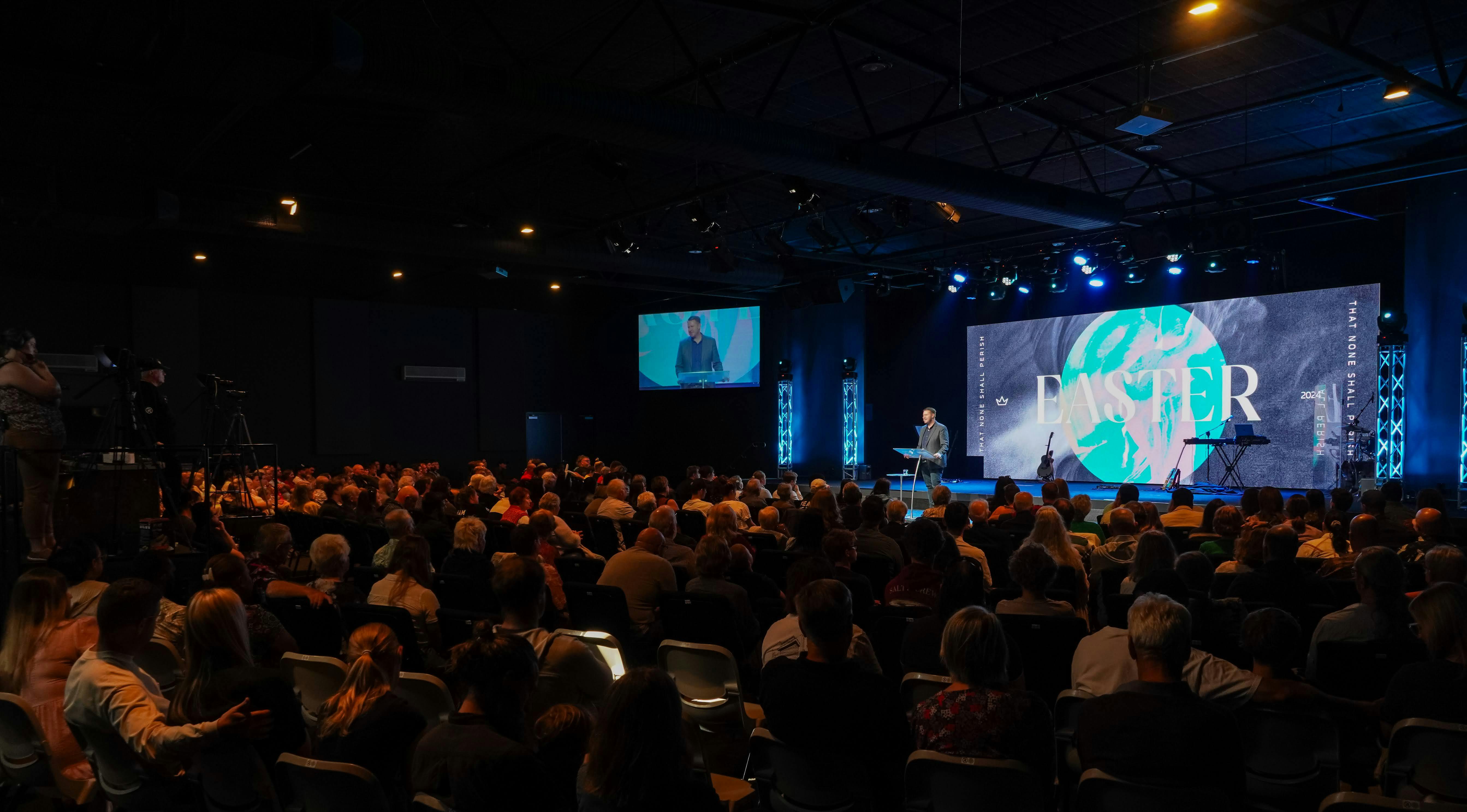 A crowd looking at a speaker on a stage.