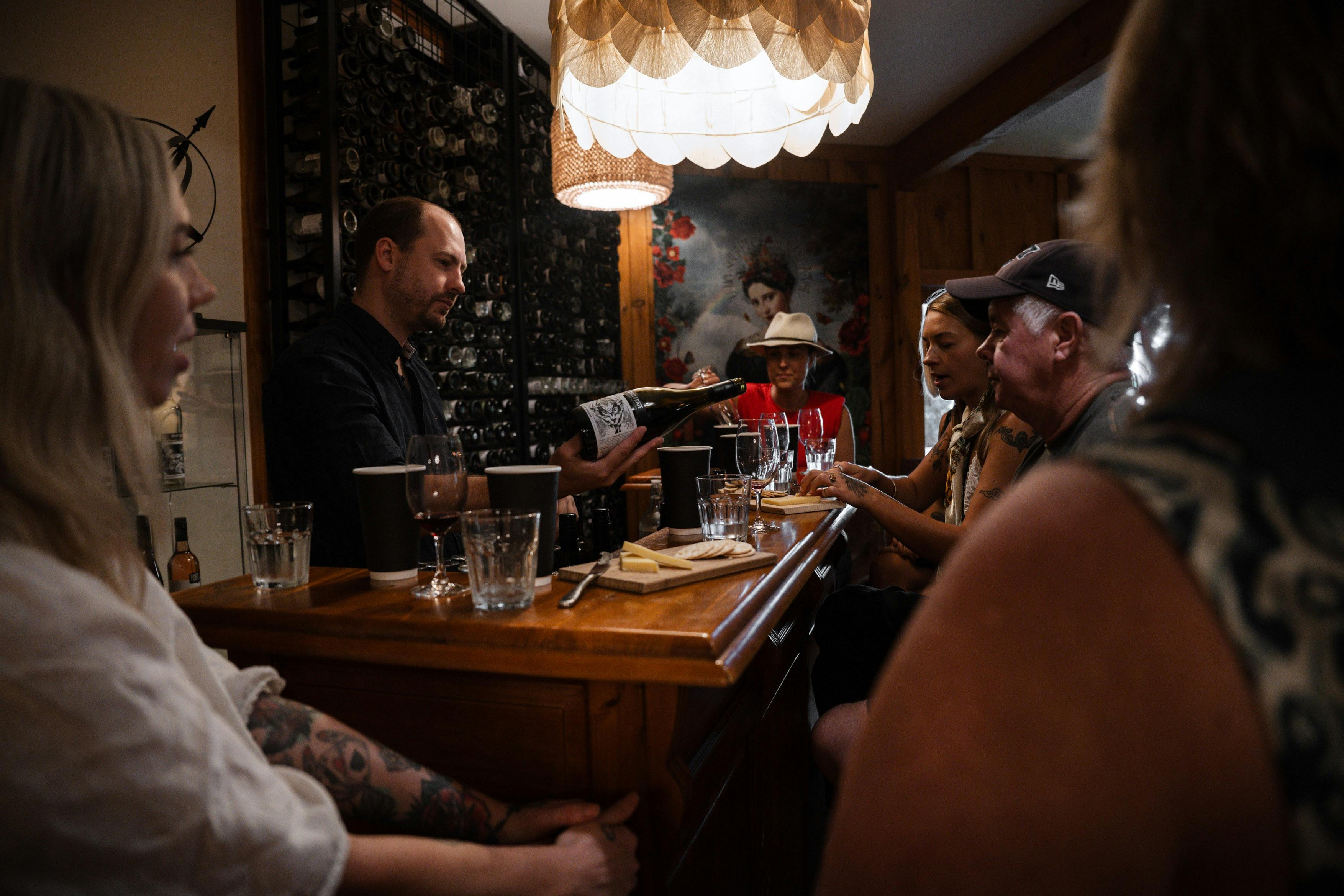 ワインメーカーがバーの周りでツアー客にワインを注ぎながらのワインテイスティング