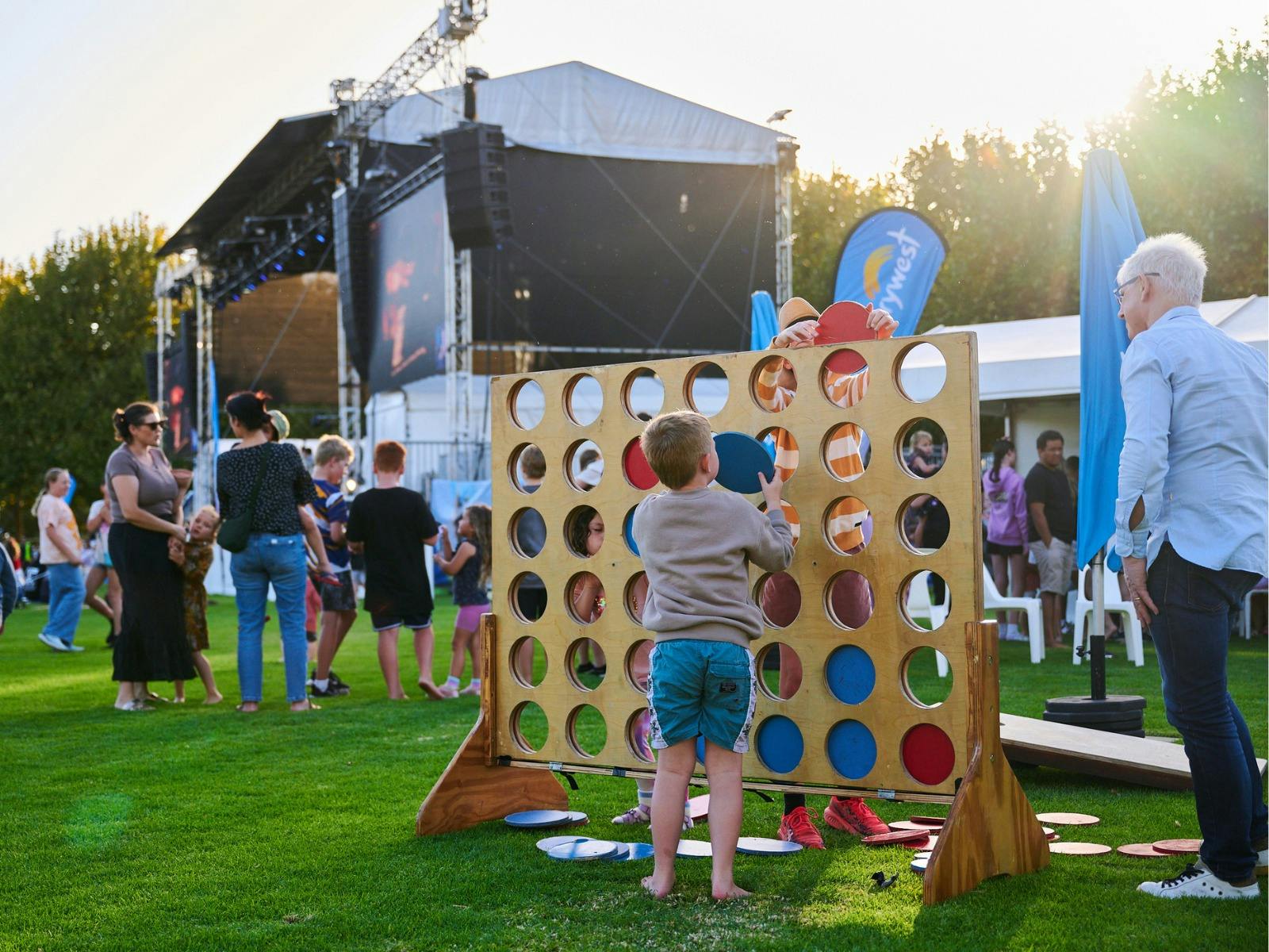 Child standing before a giant connect four game with a view of the stage in the background