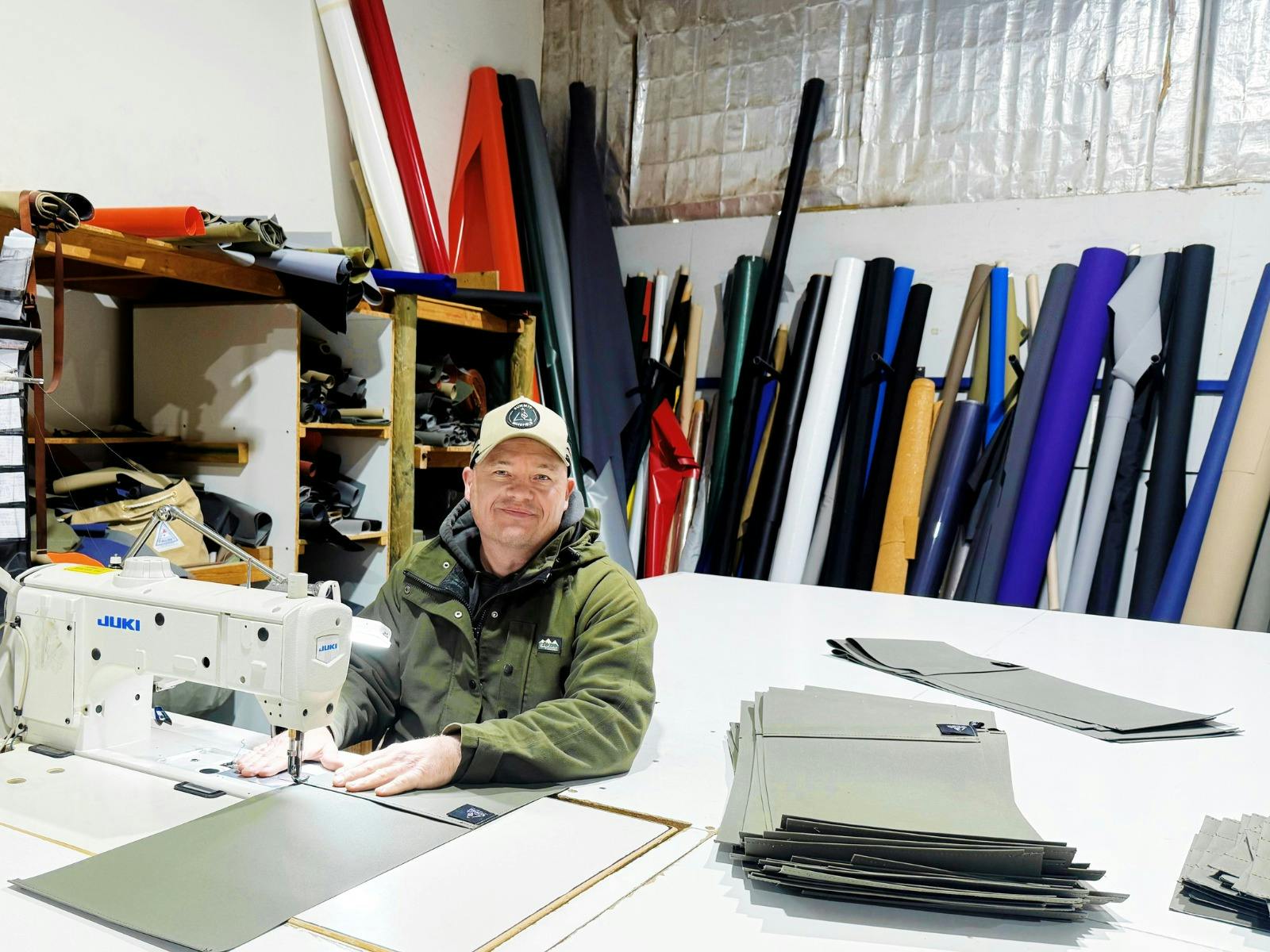 a man sitting down at a sewing machine, he is smiling