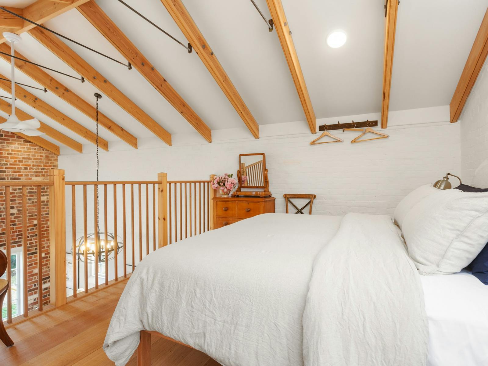 Loft bedroom with king bed, linen covers, wooden rails and ceiling
