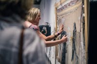 Women touch the textile weaving on the gallery wall embedded with audio feedback and sound