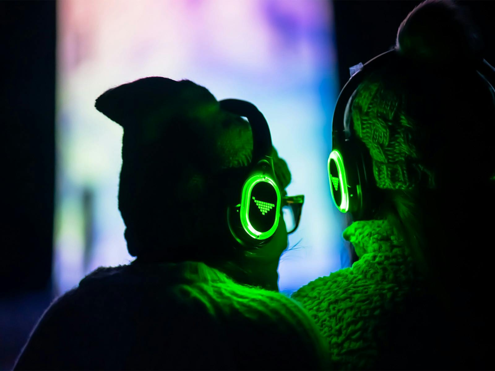 View of two people in winter woolies with headphones on listening to the narration of the light show