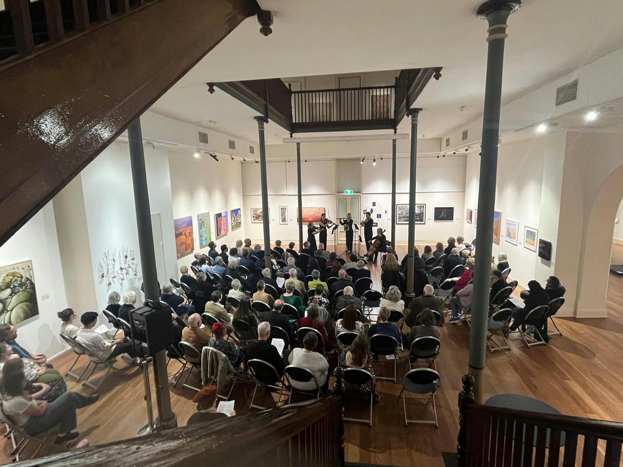 A string quartet plays in an art gallery, viewed from above