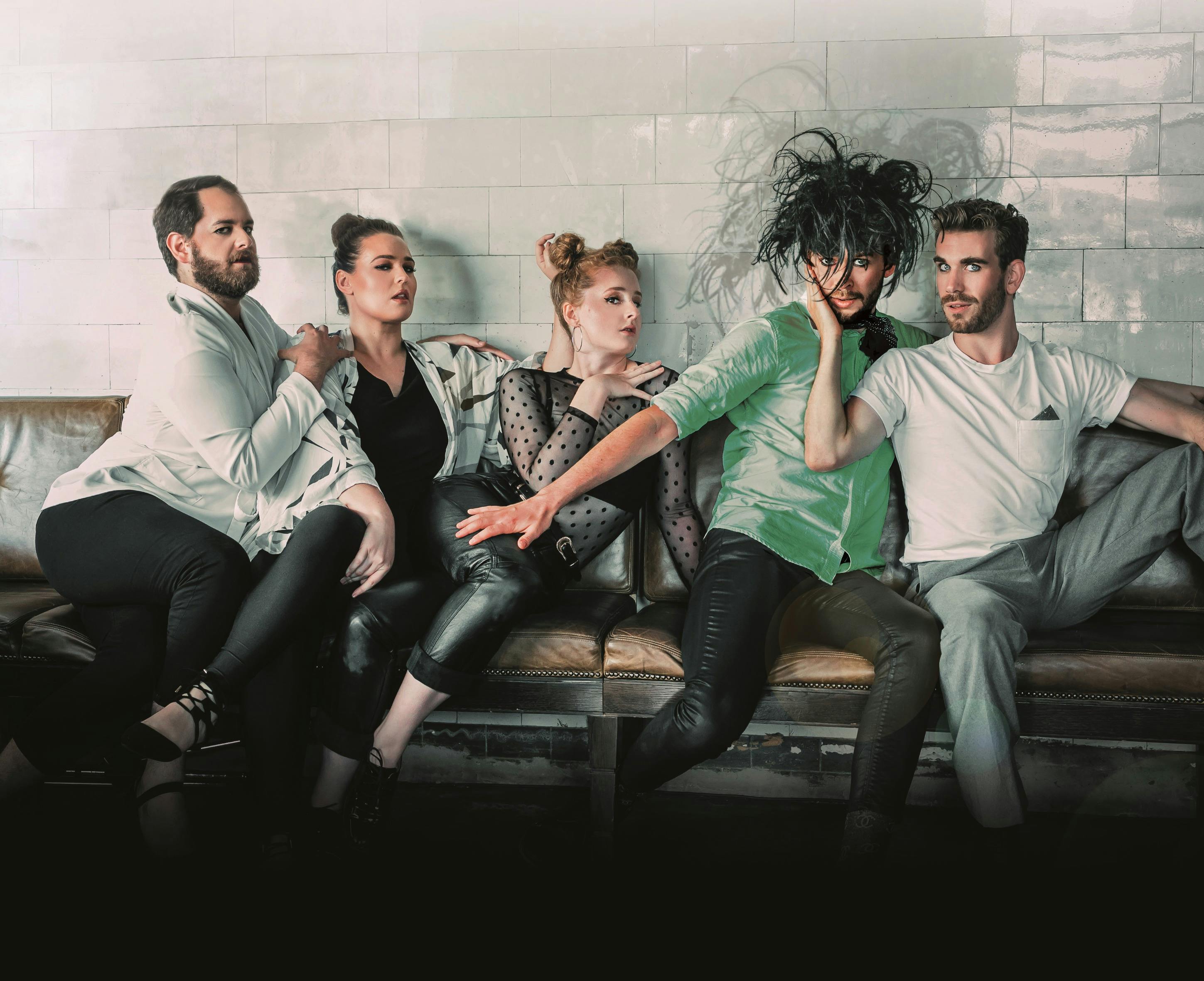 Performers from A Slightly Isolated Dog pose dramatically on a couch.