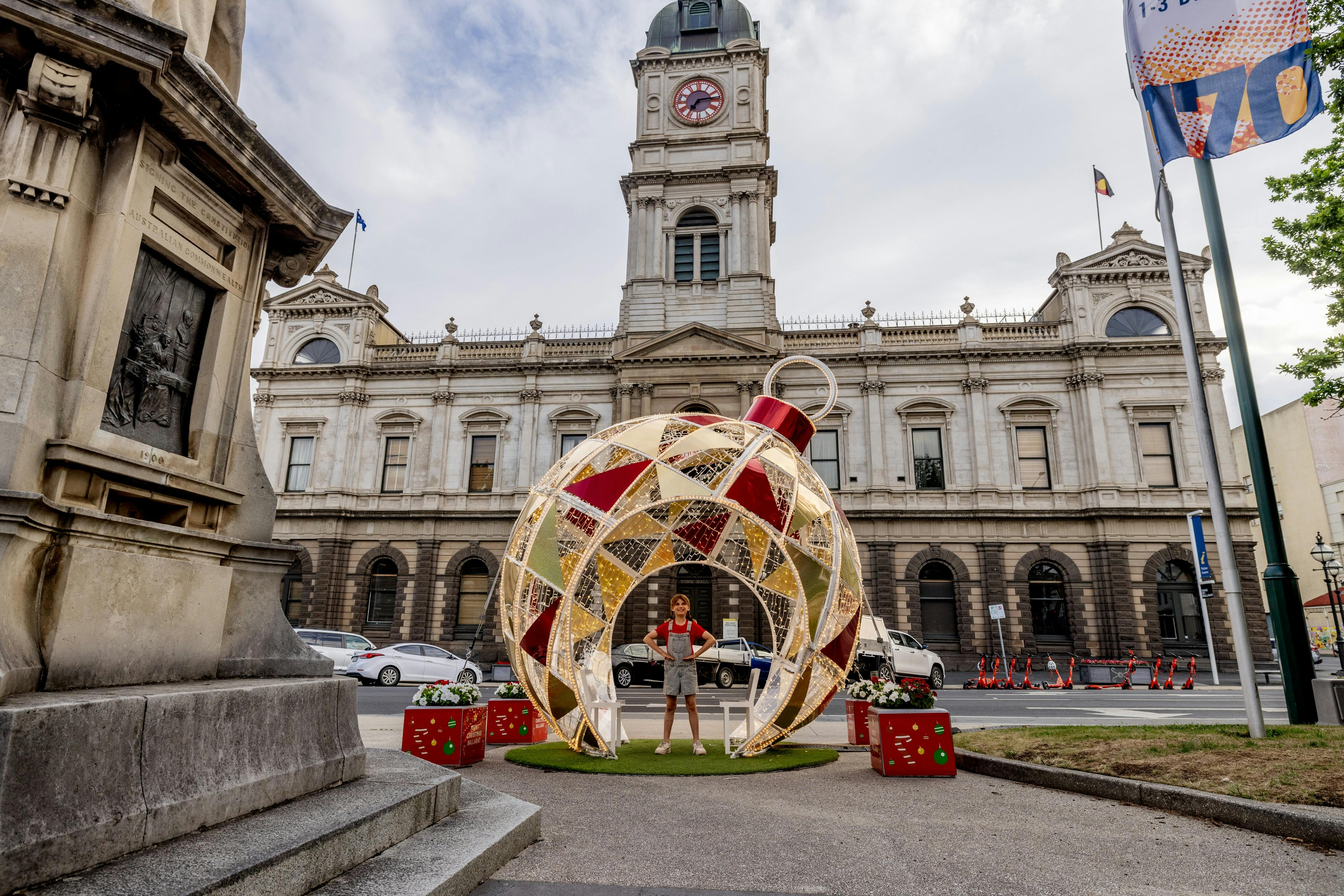 The giant Christmas Bauble sits in front of Town Hall with a little girl in red standing inside it