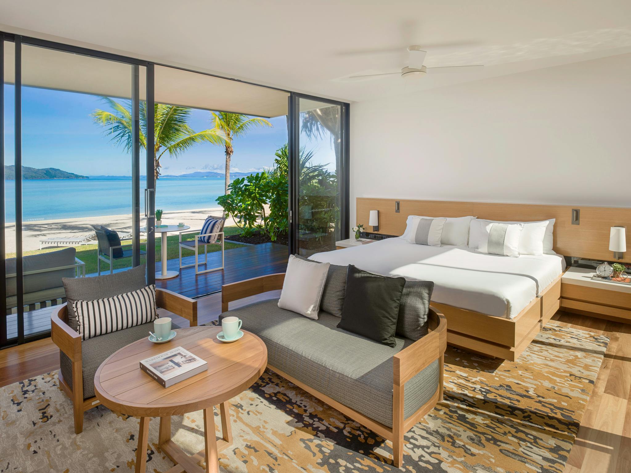 Beachfront villa with a cozy bedroom, seating area, and glass doors opening to ocean views. Beachfront villa with a cozy bedroom, seating area, and glass doors opening to ocean views.