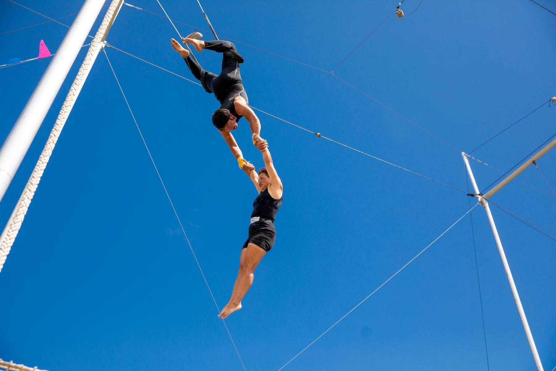 Two people performing a daring trapeze performance showcasing their strength and skill