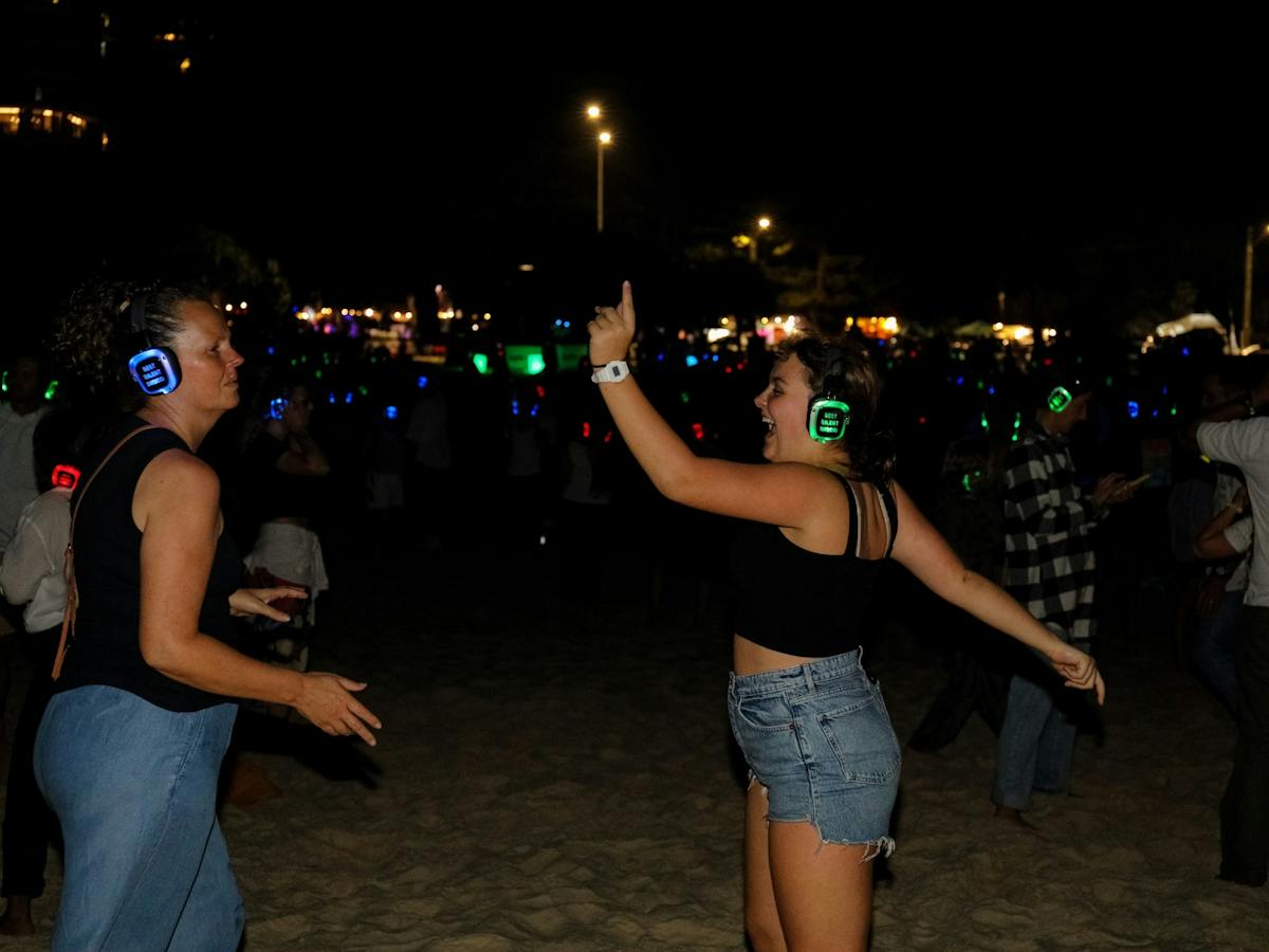 100's of people dancing on the beach atSilent Disco Under the Stars at SWELL Sculpture Festival 2024