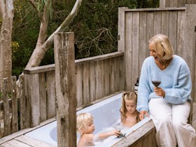 Adult sitting beside outdoor bath with children at Tea Tree Retreat accommodation in Robe South Aust