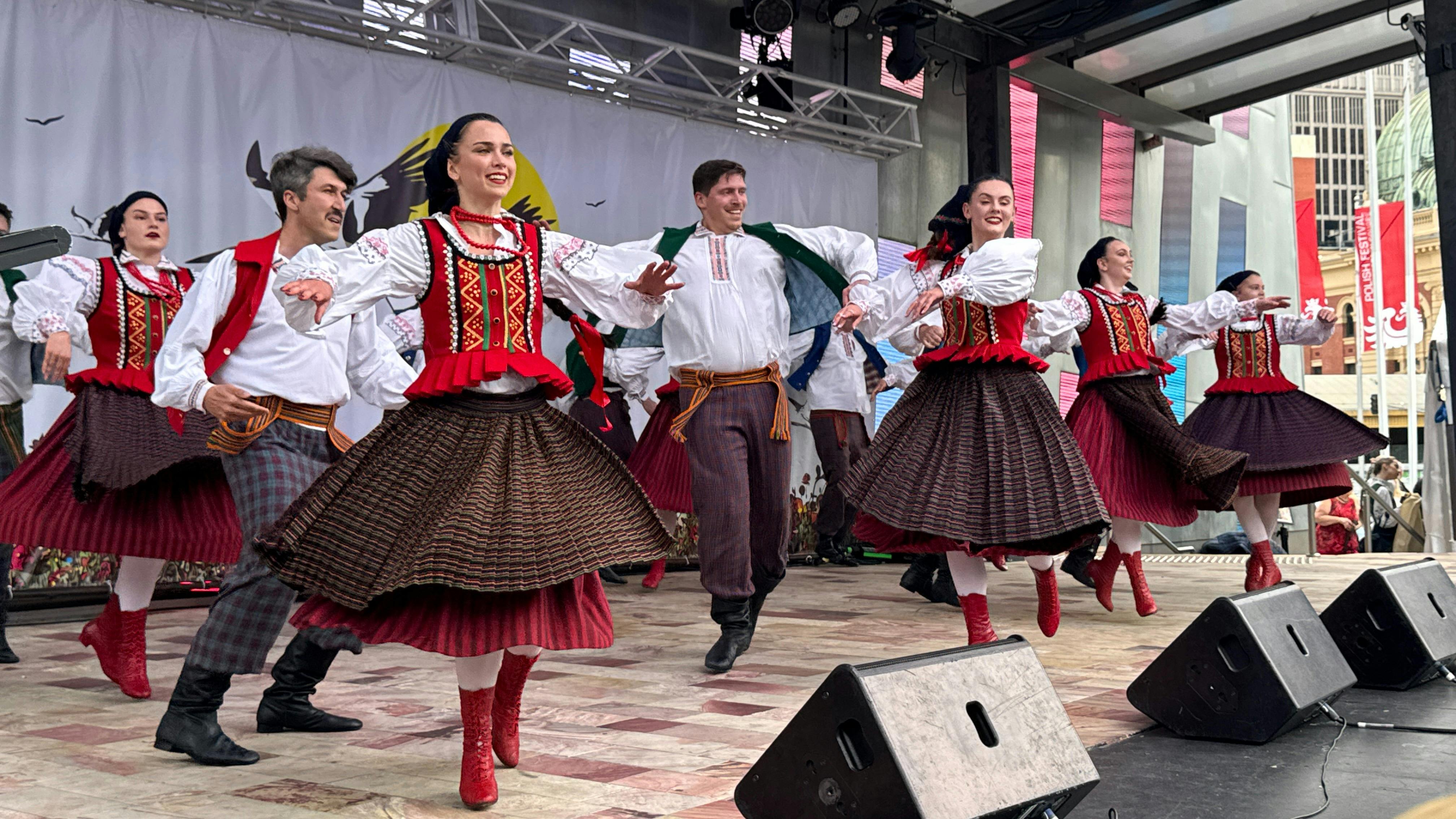 Polish folk dancers in colourful traditional costumes perform an energetic dance on stage at the Pol