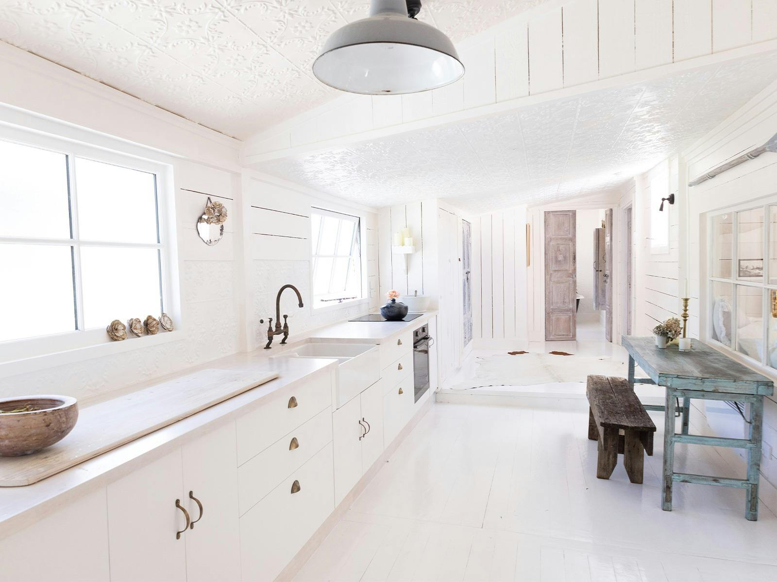 Looking down a long white gallery kitchen with pressed tin ceilings and wooden floors