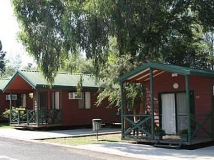 Two Cabins side by side with large shady tree branch hanging over cabin in foreground