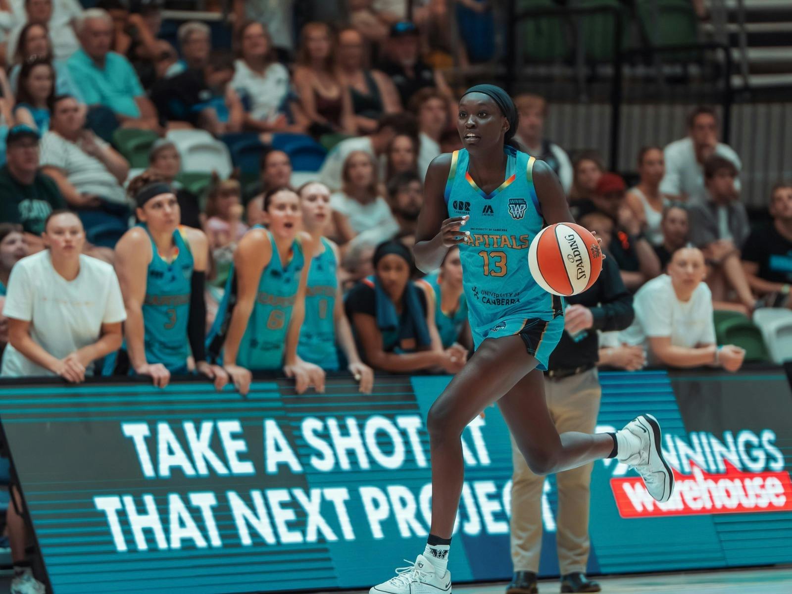 Basketball player drives down the court with the basketball.