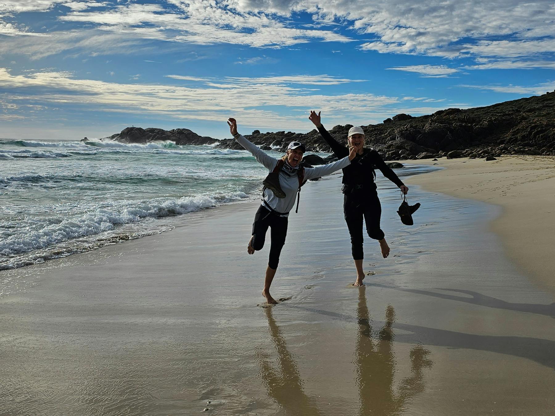 Happy hikers with no shoes on walking in water at Smith's Beach