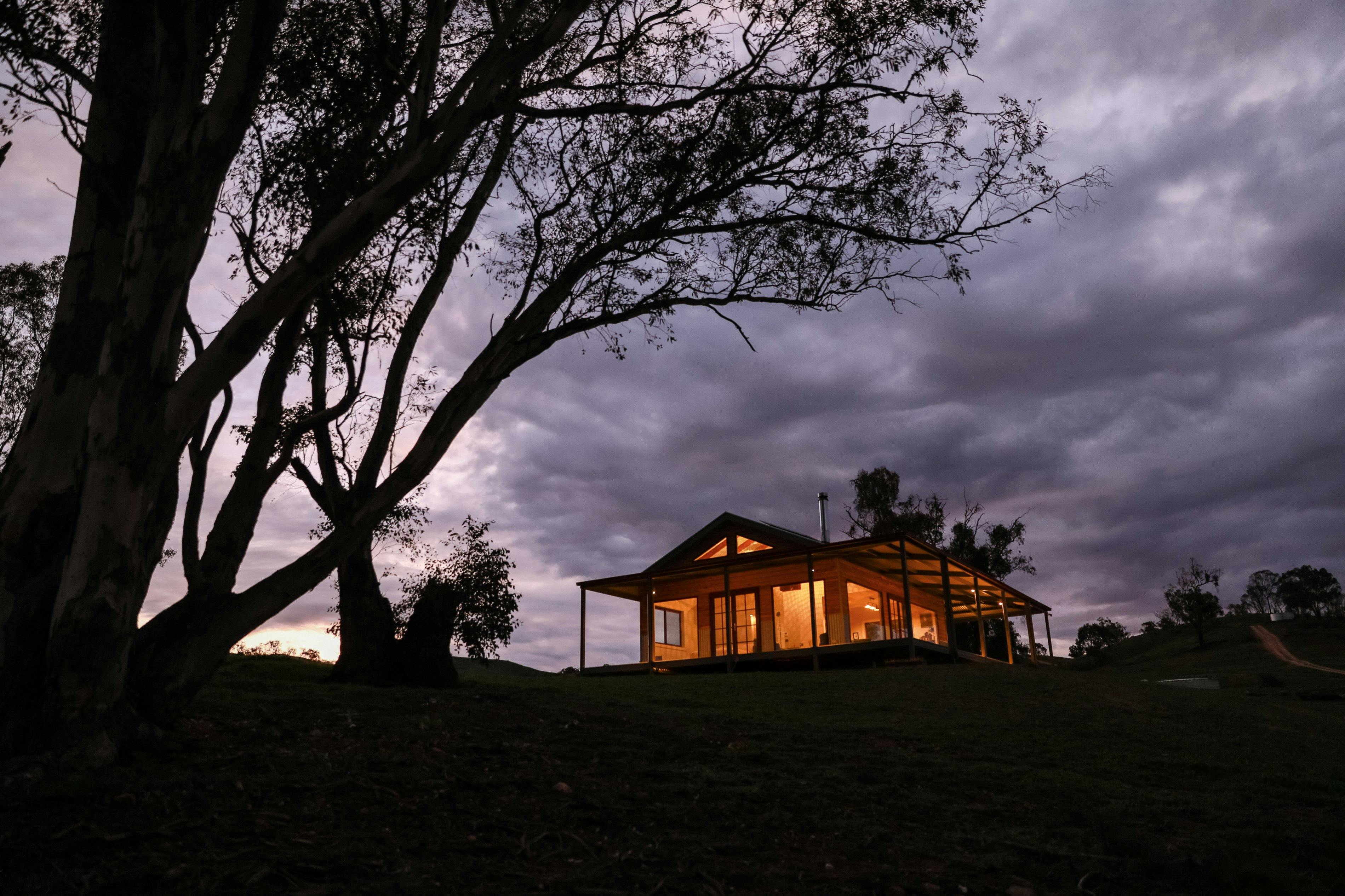 雰囲気のある空を背景にした夜の画像。ケストレル ネスト エコハットの中から金色の光が輝いています。