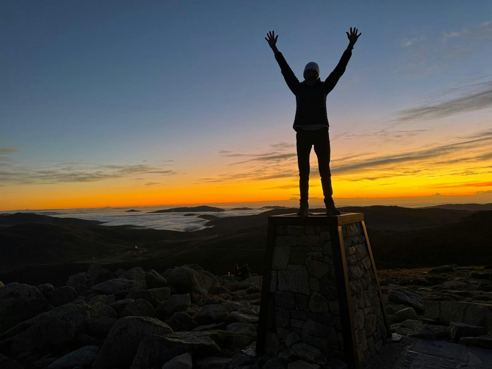 Women with arms raised, sunrise on top of Australia, orange skies in the background