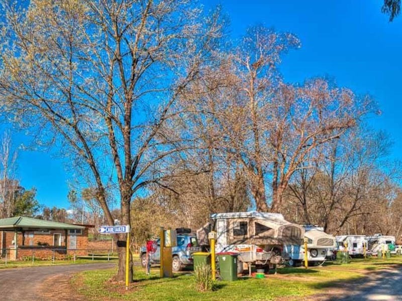 Image of a road which splits in two - leading to amenities building one side and caravans the other