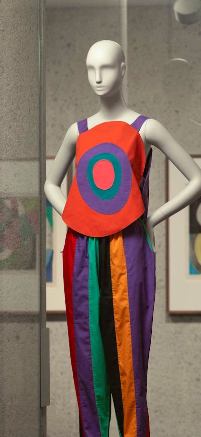 A photograph of three colourful, patchwork outfits on mannequins in a gallery