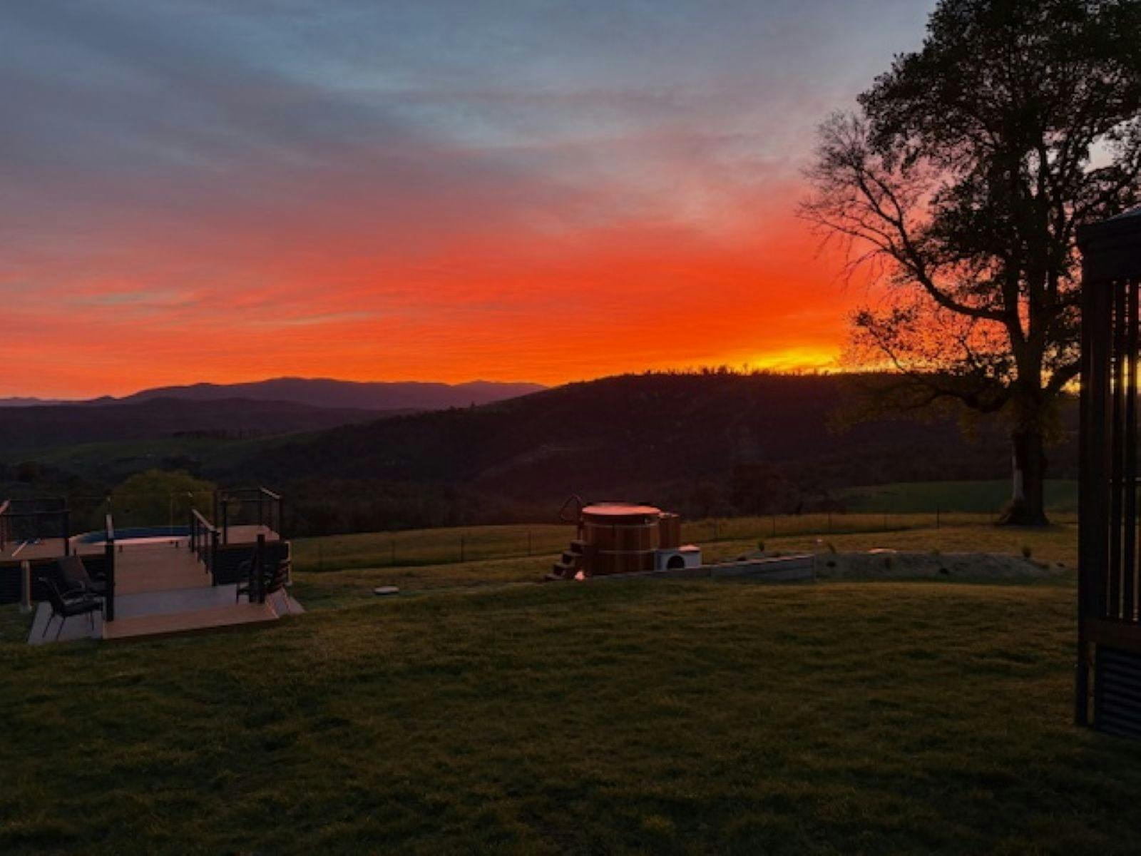 山々のシルエットと広々とした草原が広がる田園地帯に沈む夕日。