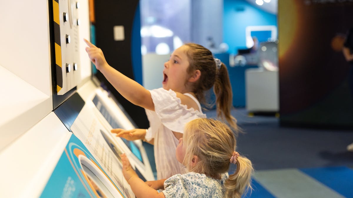 Two excited children interacting with the buttons in the interactive exhibit