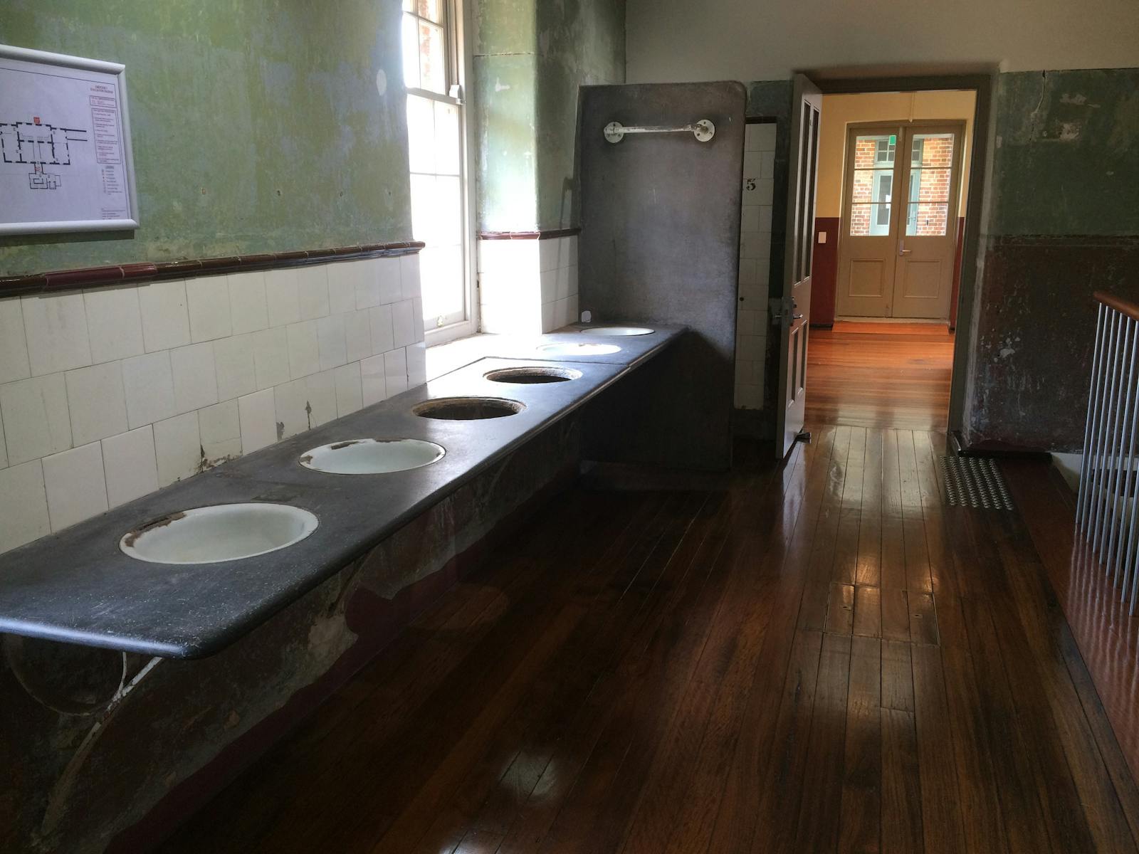 Looking down corridor with Heritage wash basins, wooden floors and sunlight coming through window