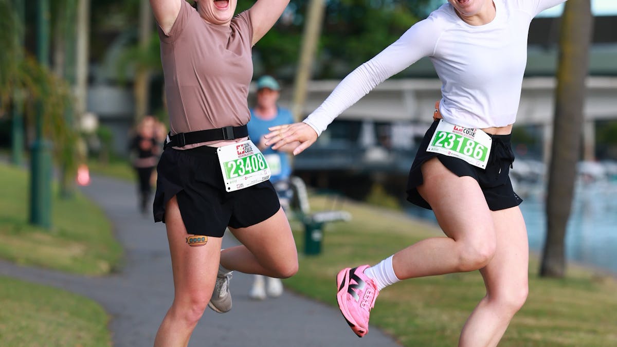 Two excited female runners jumping for the photo.