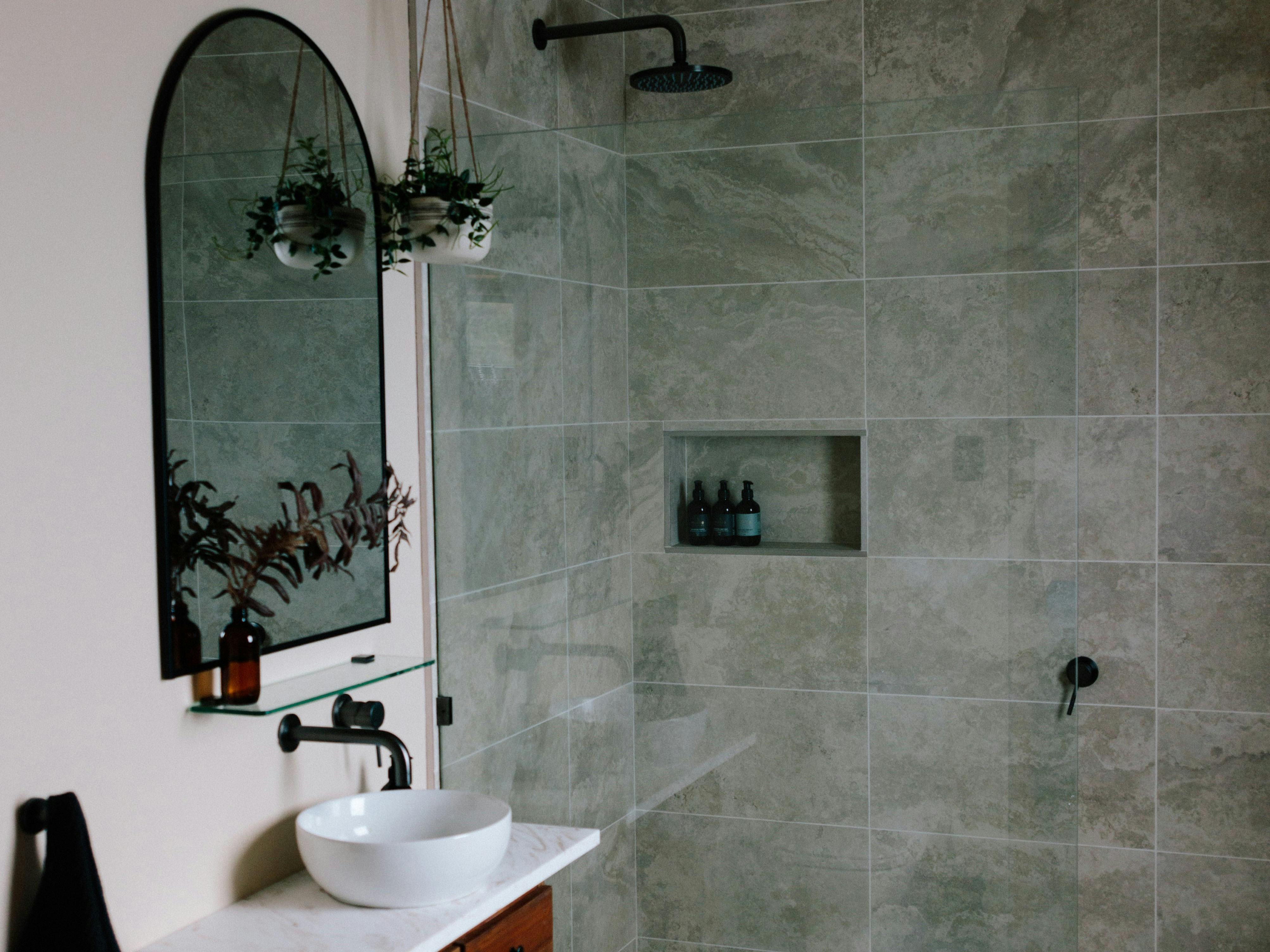 A bathroom scene with sink, mirror and shower