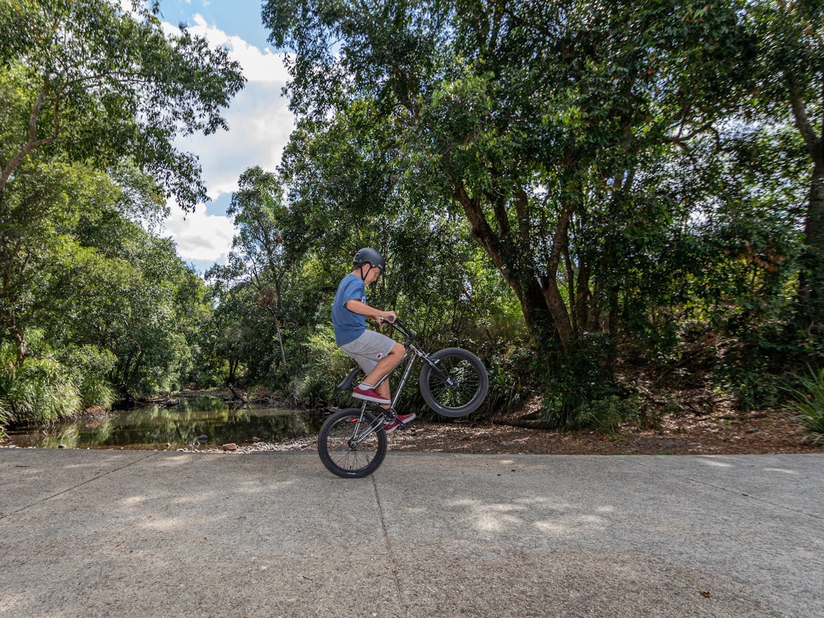 A boy doing a wheelie on his bike on the Samford Valley Rail Trail