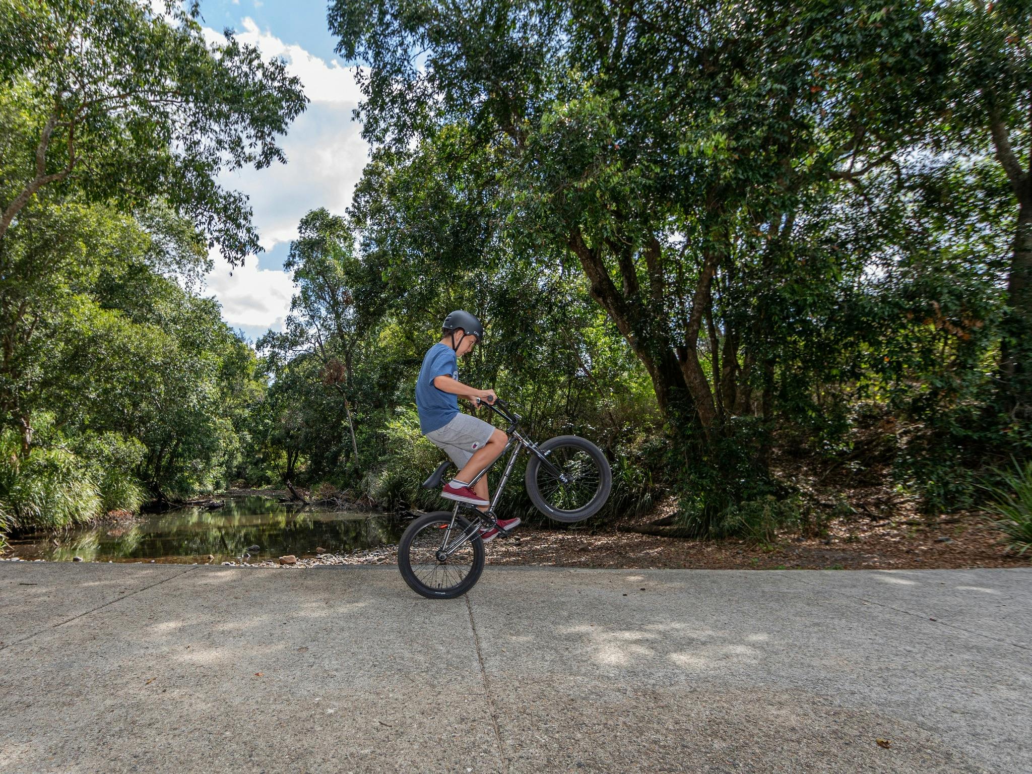 A boy doing a wheelie on his bike on the Samford Valley Rail Trail A boy doing a wheelie on his bike on the Samford Valley Rail Trail