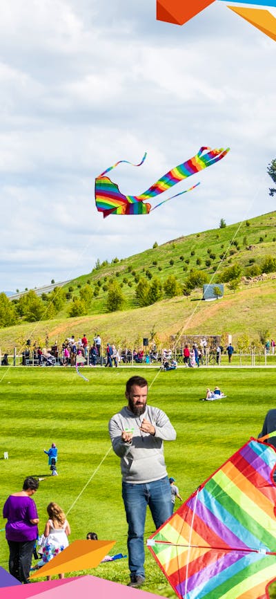 Families flying kites outdoors with colourful graphic overlay