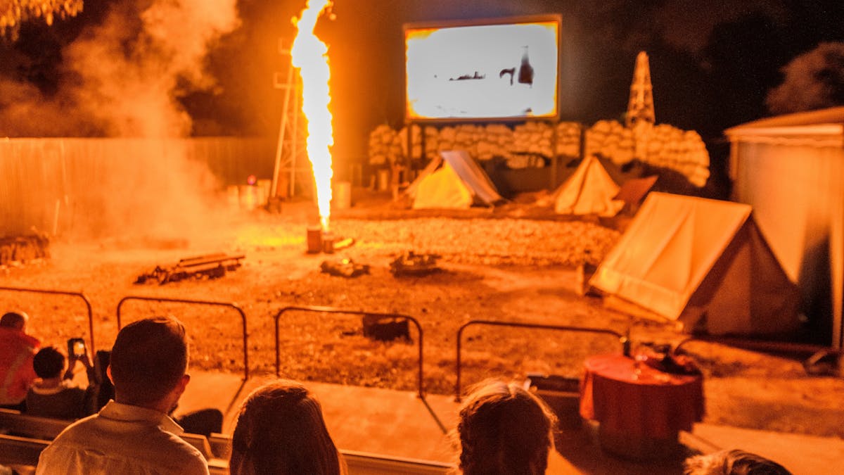 A family watching fire shoot from the ground during the Night Show