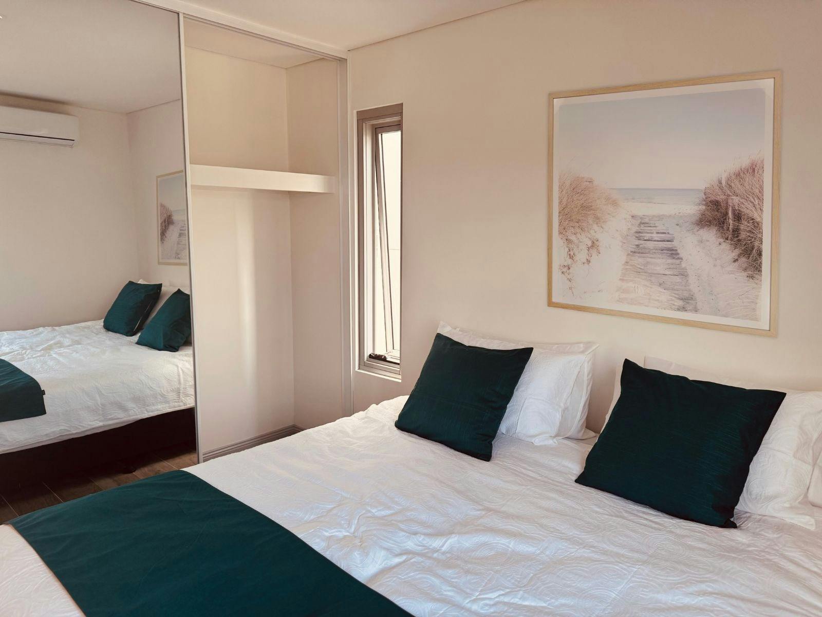 鏡付きの収納スペースを備えたベッドルーム（キングサイズのシングルベッド2台が隣接）