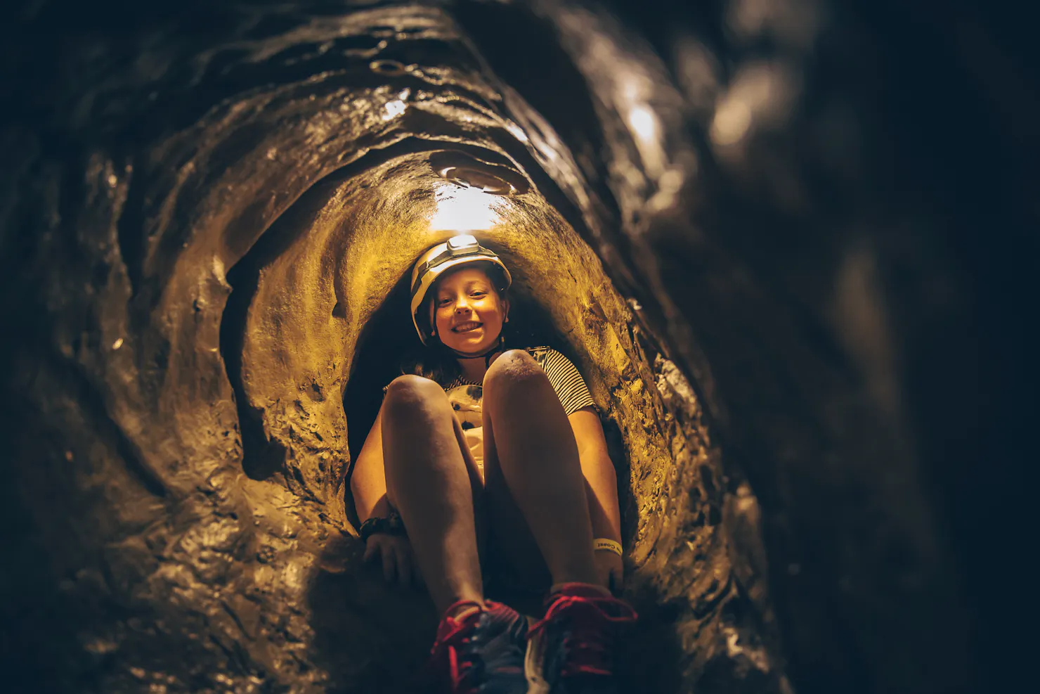 a teenager with a headlamp exploring the indoor caving system