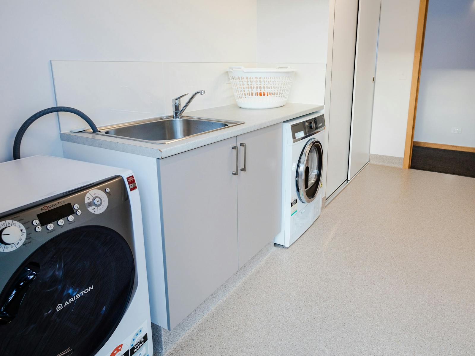 The laundry has a front-loading washing machine, separate tumble dryer and a large tub
