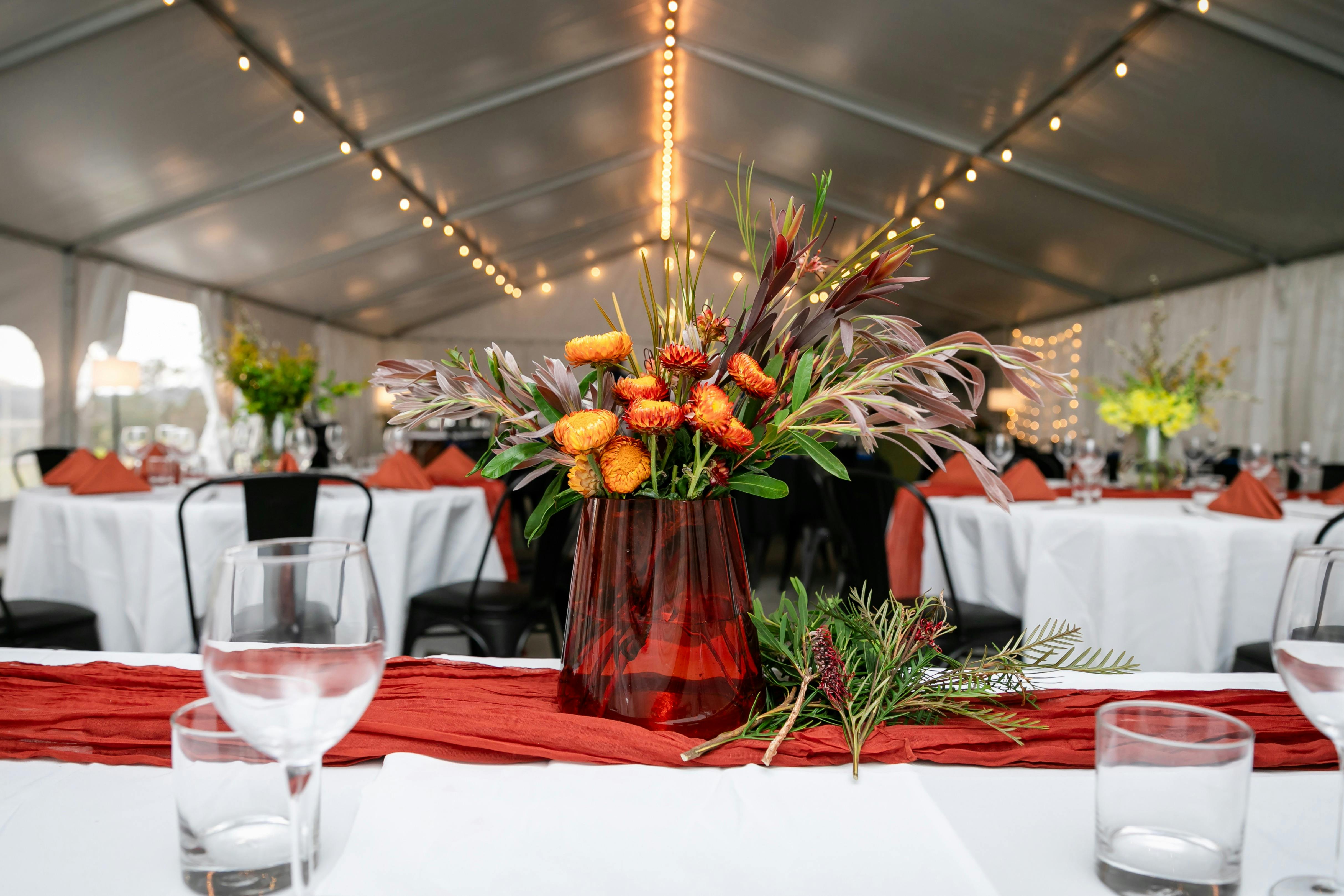 view of the seating in the wedding marquee. Terracotta styling with local flowers
