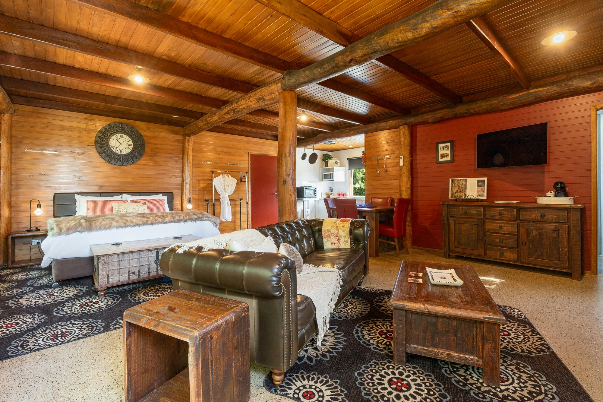 Cosy interior of the shack includes wooden walls and ceiling, and concrete floor with dark furniture