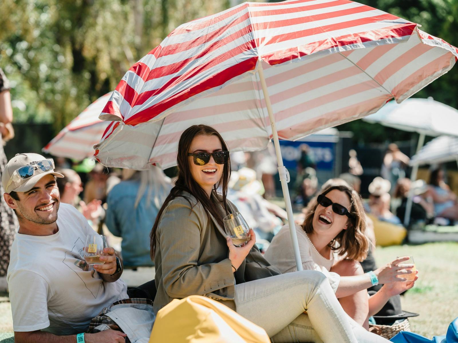 Image of three people at the Tasmanian Wine Festival, under a sun umbrella